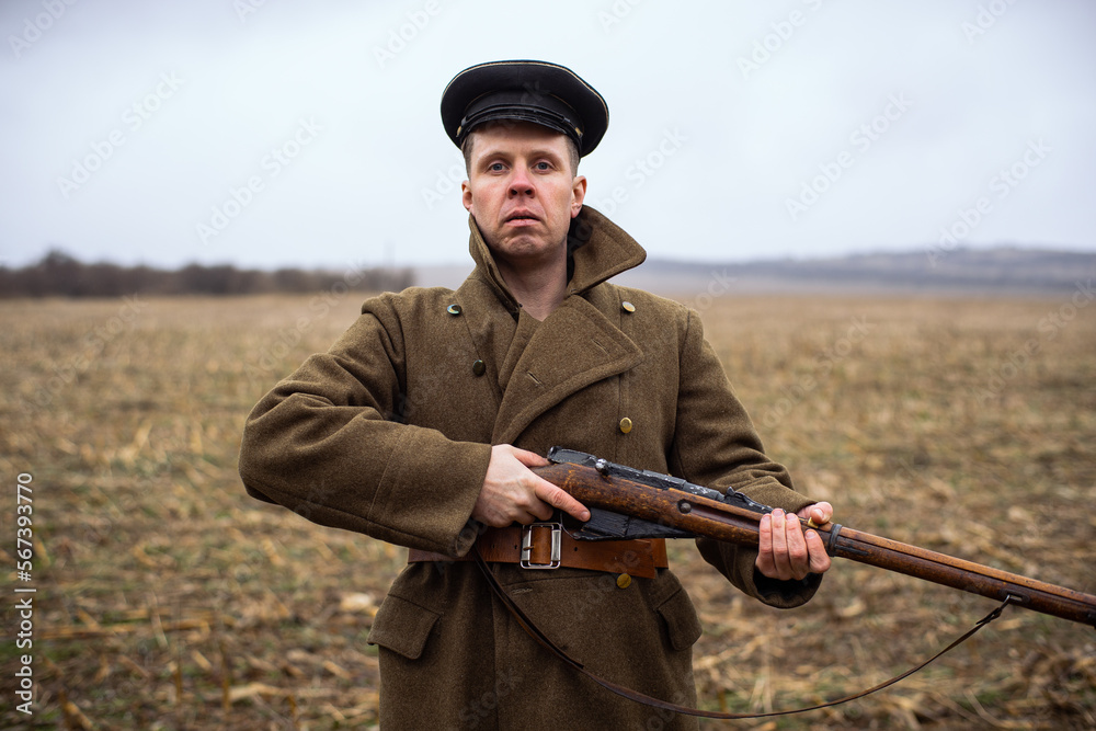 retro soldier with a rifle in his hands is looking at the camera. First World War soldier in uniform coat and hat. autumn retro soldier with a rifle in his hands is looking at the camera. First World War soldier in uniform coat and hat. autumn