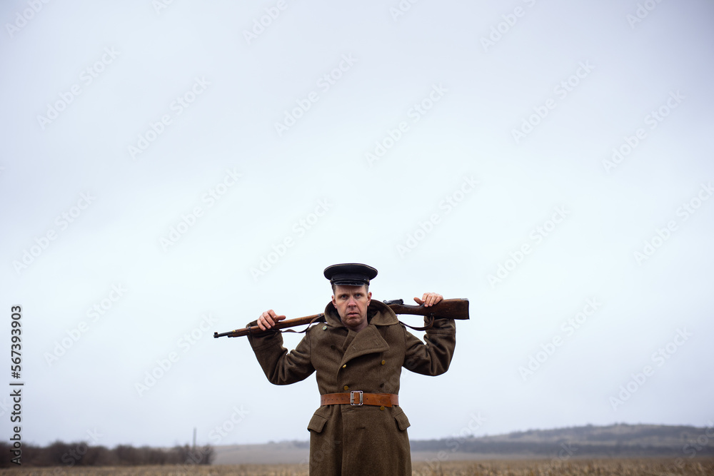 a cool retro soldier of the first world war boldly holds a weapon around his neck and looks evilly at the camera. soldier of the ussr 1990s - obrazy, fototapety, plakaty 