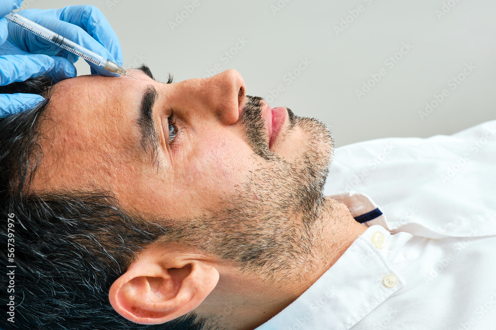 45-year-old dark-haired man in an aesthetic clinic being treated with botulinum toxin 45-year-old dark-haired man in an aesthetic clinic being treated with botulinum toxin