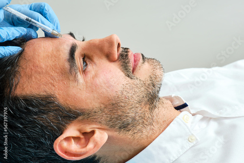 45-year-old dark-haired man in an aesthetic clinic being treated with botulinum toxin