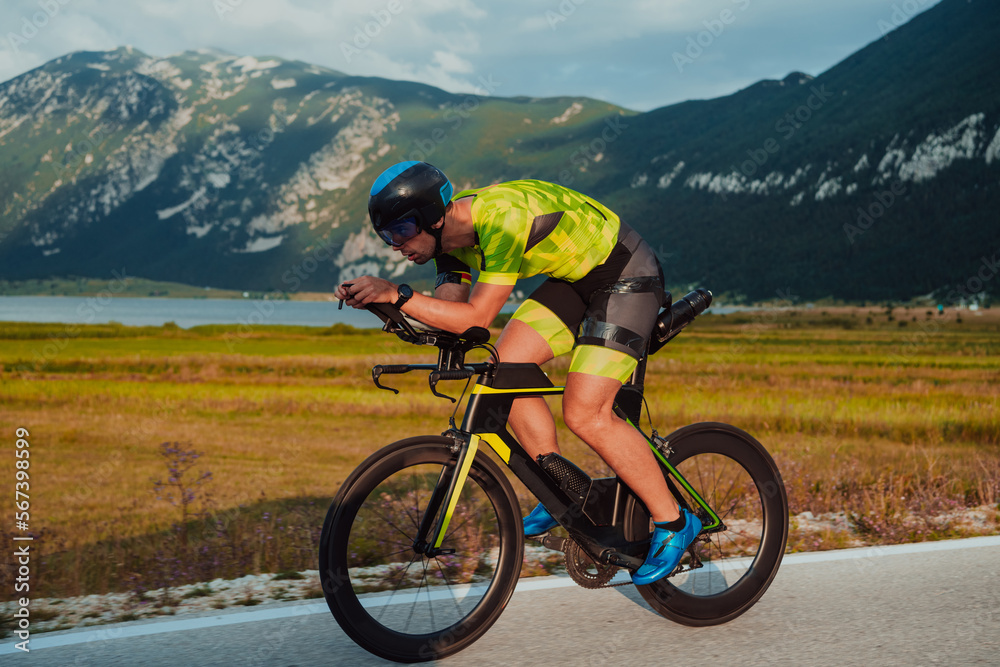 Full length portrait of an active triathlete in sportswear and with a protective helmet riding a bicycle. Selective focus 