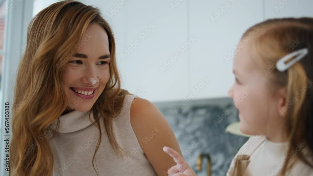 Playful child touching mother nose kitchen close up. Woman and girl having fun Playful child touching mother nose kitchen close up. Woman and girl having fun