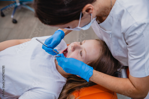 A girl of European appearance of 10 years old receives dental treatment in a dental clinic. Close-up. View from above