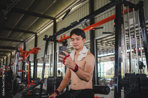 Asian men using mobile phones for selfies after exercise at the gym