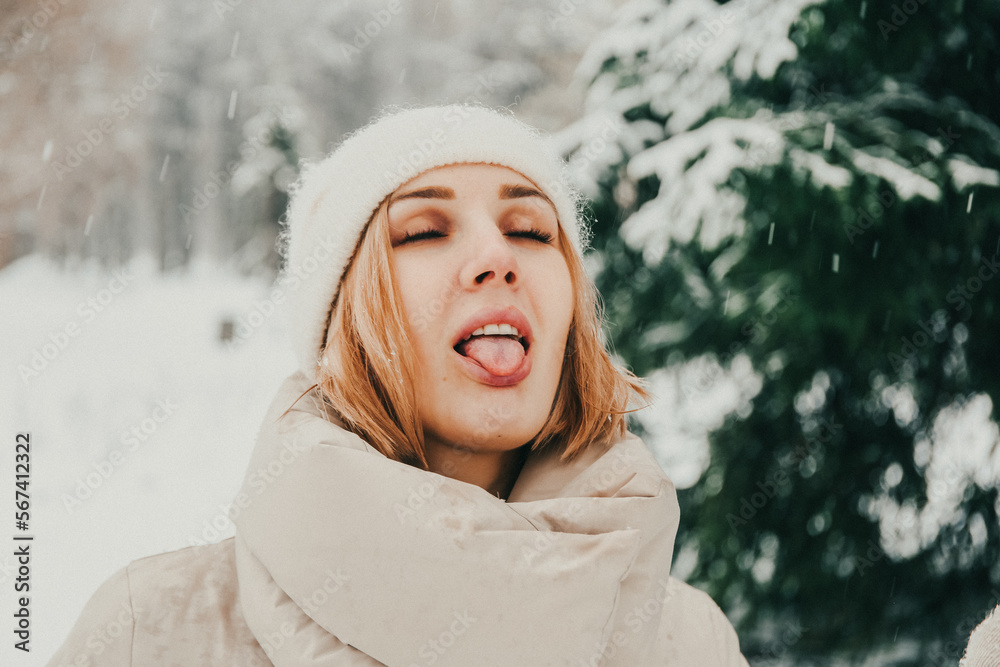 A girl in a beige coat catches snowflakes with her tongue in the forest A girl in a beige coat catches snowflakes with her tongue in the forest