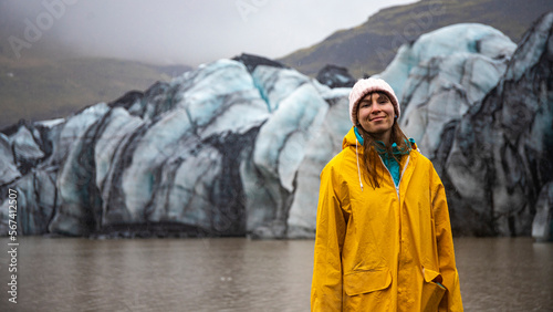 Portrait of a beautiful girl wearing a yellow raincoat with a hood on the background of the katla glacier, southern Iceland.  photo