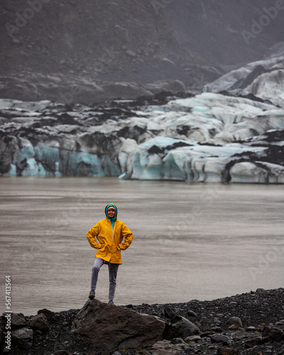 Beautiful girl in a yellow raincoat admires the powerful big Katla glacier during rainy weather in southern Iceland photo