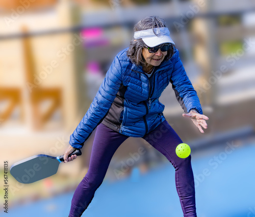 Woman wears warm coat to play pickle ball in the winter outdoors.tif photo