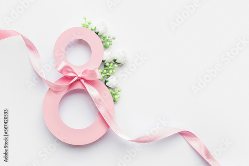 Pink paper cut eight with ribbon on white background. Postcard March 8 concept