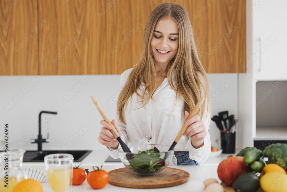 A cute blonde woman is preparing a salad in the kitchen A cute blonde woman is preparing a salad in the kitchen