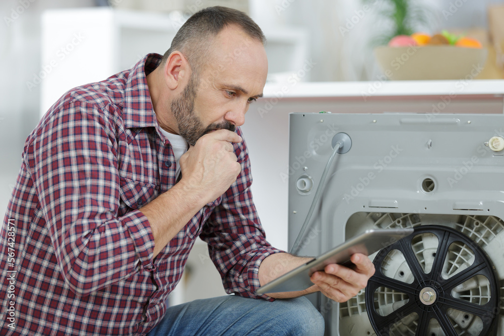 man using tablet to fix a washing machine