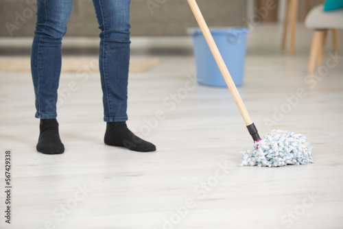 detail of woman holding a floor wiper and wiping floor