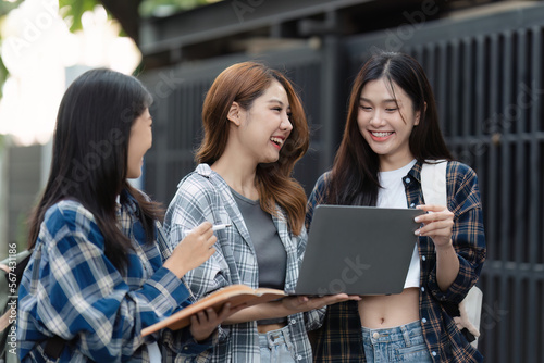 Beautiful young Asian woman college student with friends at outdoors. College student working on the college campus