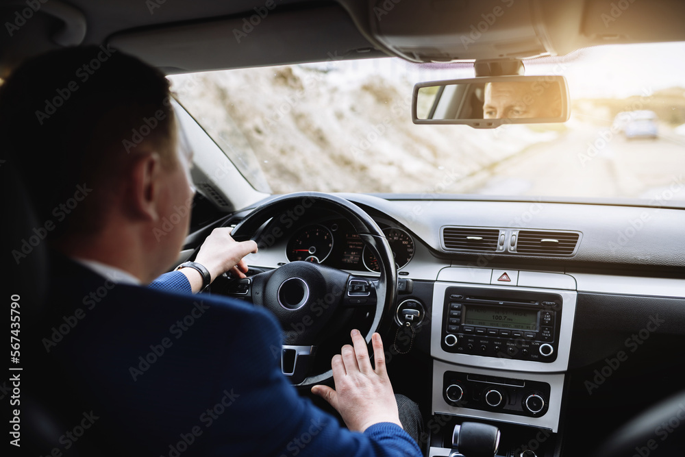 On the way to success. Confident and young businessman in stylish suit is driving his new luxury car and smiling. Entrepreneur traveling to work business travel social distancing. On the way to success. Confident and young businessman in stylish suit is driving his new luxury car and smiling. Entrepreneur traveling to work business travel social distancing.