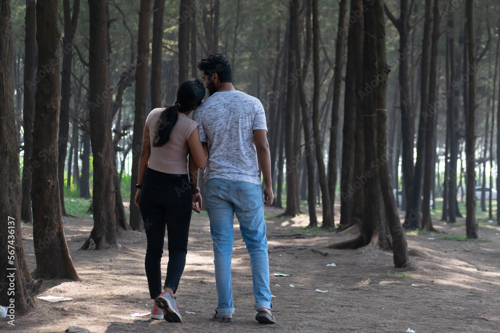 Beautiful young attractive tourist couple looking each other embracing, loving smiling cuddling walking in woods. Beautiful young attractive tourist couple looking each other embracing, loving smiling cuddling walking in woods.