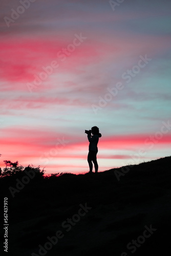 Femme qui prend une photo au coucher du soleil