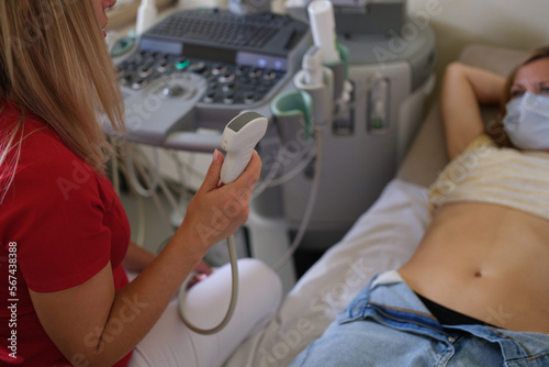 The doctor makes an ultrasound of the abdomen to woman