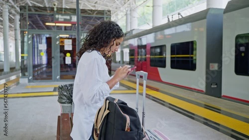 Young woman using phone while waiting train boarding at the station