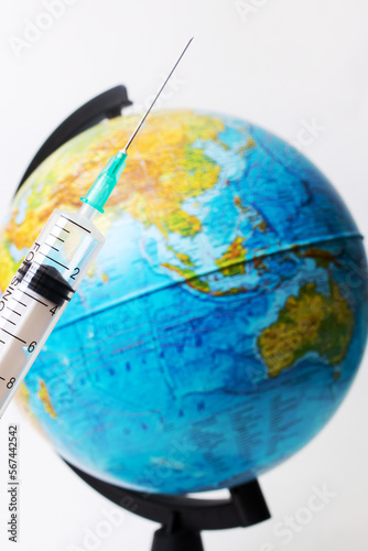 Syringe in hand on background of globe