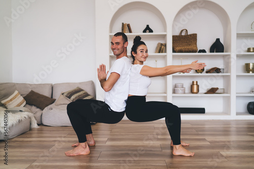Happy couple doing yoga practice in living room