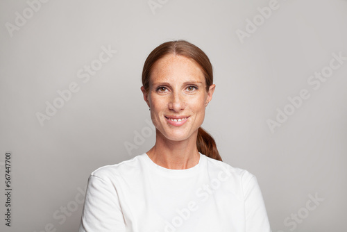 Cute mid adult woman smiling, indoor studio portrait. Female face closeup.
