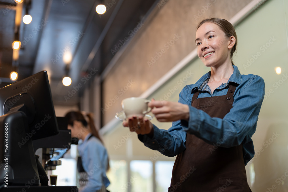 Female barista in apron smiling and serving cup of hot coffee to client in coffee shop. Barista owners small business.