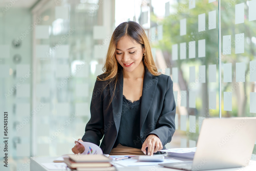 Asian businesswoman working with laptop computer using calculator to calculate business finance and accounting statistics at office. Asian businesswoman working with laptop computer using calculator to calculate business finance and accounting statistics at office.