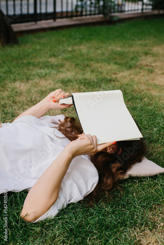 Magazine or book image mockup. The girl relaxes on the lawn in the courtyard of the coffee shop, reads a book. photo