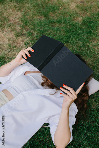 Magazine or book image mockup. The girl relaxes on the lawn in the courtyard of the coffee shop, reads a book. photo