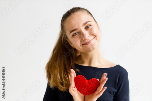 Positive young woman holding a red heart in her hands, portrait. Sports and healthy lifestyle.