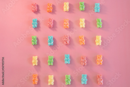 Styled Bulk Vintage Candy. Sour Coated Rainbow Gummy Bears Lined up on Pink Background. Valentines Day Candy Flat Lay. photo