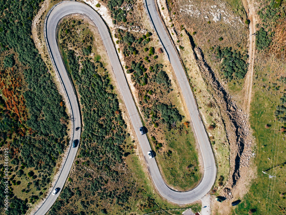 Obraz premium Aerial view of winding road. Splendid morning scene of asphalt roadway. Highway through the woodland . Traveling concept background.