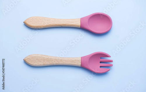 A set of colored silicone forks and spoons with a wooden handle. Baby feeding and nutrition concept. Top view, flat lay.