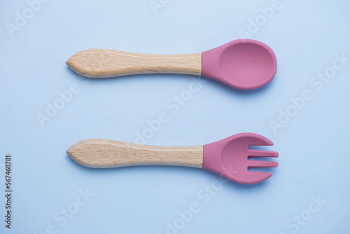 A set of colored silicone forks and spoons with a wooden handle. Baby feeding and nutrition concept. Top view, flat lay.