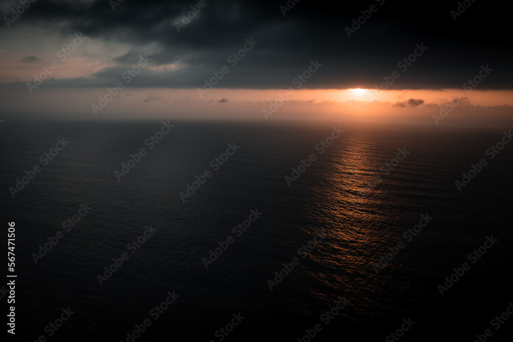 Naklejka premium drone view of the ocean and the sun hidden in the clouds