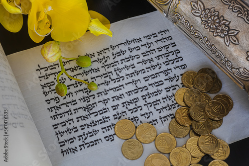 Open Megillat Esther [Megillah, Megila] (Scroll, Book of Esther) isolated scroll on black background and coins, flowers, silver. Read on the Jewish holiday of Purim photo