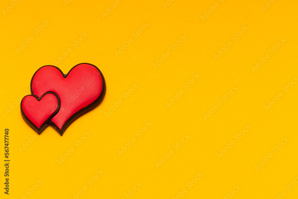 Two red hearts on a yellow background with copy space. Place for text. Postcard for congratulations. Valentine's Day.