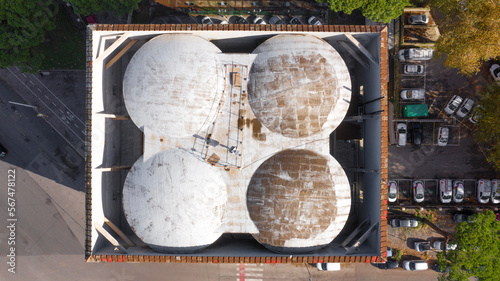 Perpendicular aerial view of the roof of a building in a big city. Above it there is a walkable terrace where antennas and satellite dishes have been installed. On the street there are auto. photo