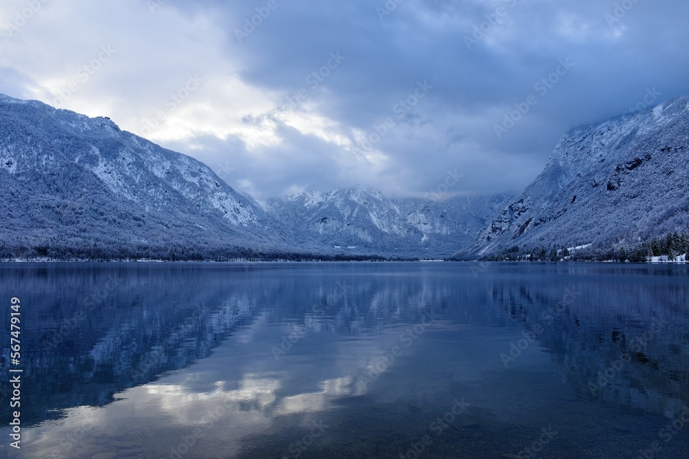 View of Bohinj lake in Gorenjska, Slovenia in winter with forest covered mountains in Julian alps