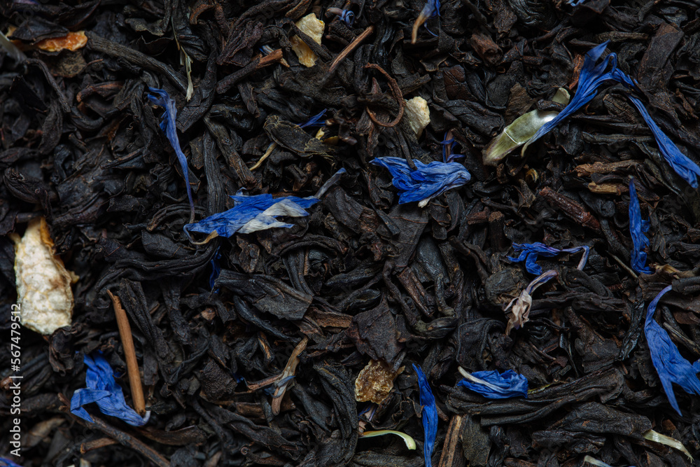 Closeup of black tea with orange, lemon peels and cornflower petals background Closeup of black tea with orange, lemon peels and cornflower petals background