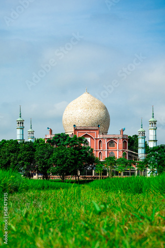 Mosque against backdrop of rice field and blue sky. photo