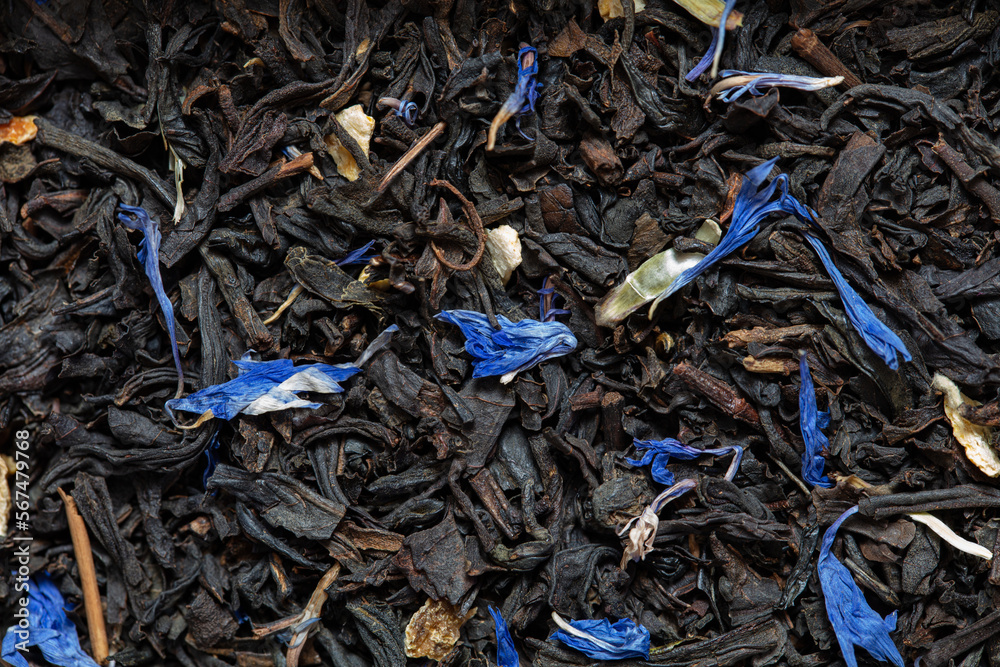 Closeup of black tea with orange, lemon peels and cornflower petals background Closeup of black tea with orange, lemon peels and cornflower petals background