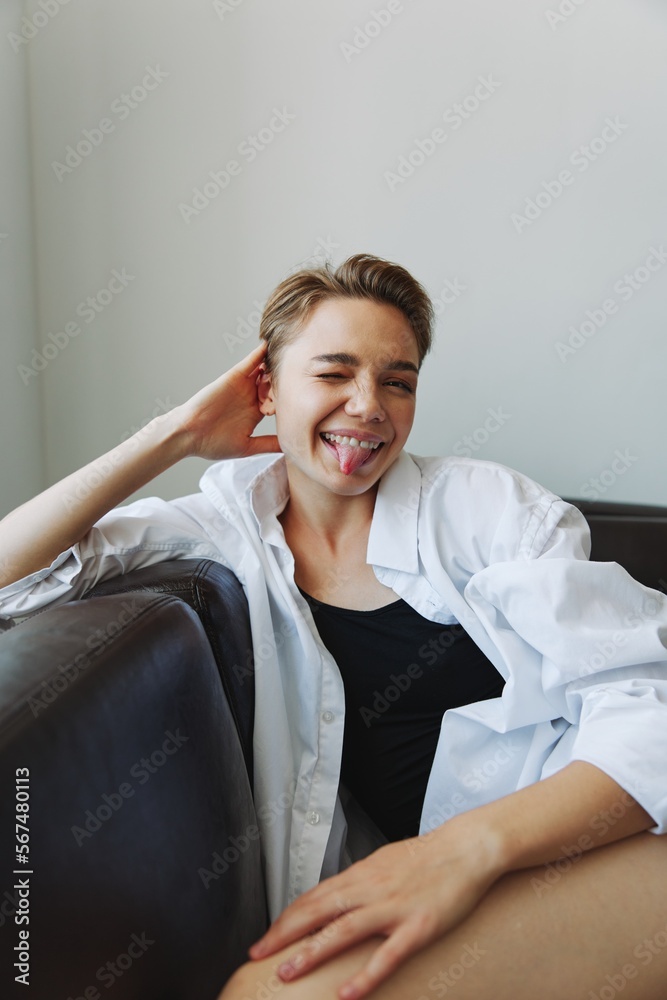 Women lying at home on the couch portrait with a short haircut in a white shirt, smile, depression in teenagers, home holiday Women lying at home on the couch portrait with a short haircut in a white shirt, smile, depression in teenagers, home holiday
