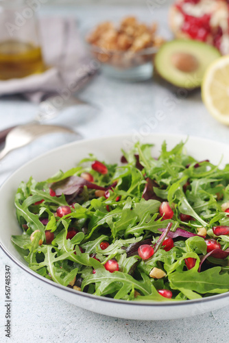 A plate with green rocket salad with pomegranate	