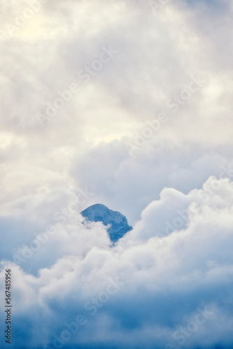 mountaintop peeking through fluffy cumulus clouds after sunset