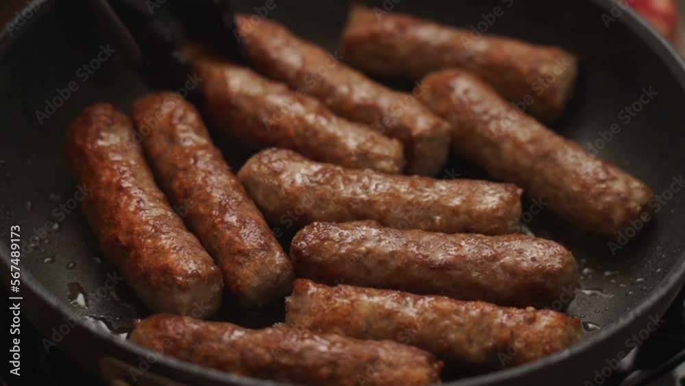 Crop person turning homemade sausages frying in pan Crop person turning homemade sausages frying in pan
