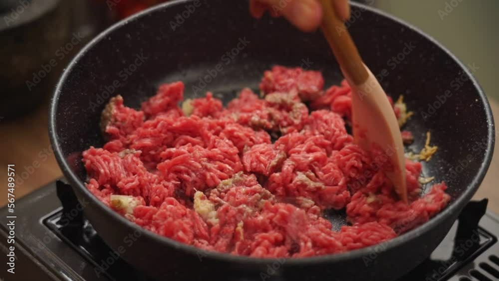 Crop cook frying minced meat in pan Crop cook frying minced meat in pan