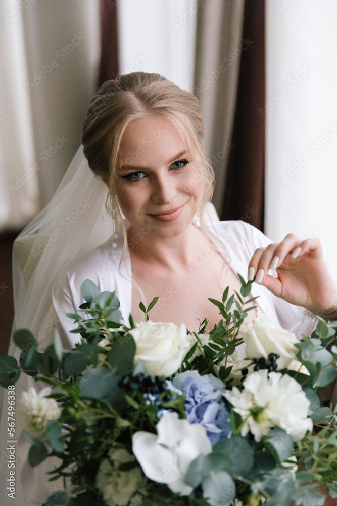 Morning preparations of a beautiful, sexy bride with a wedding bouquet in lingerie, a bathrobe in a hotel, where she puts on shoes in a wedding dress Morning preparations of a beautiful, sexy bride with a wedding bouquet in lingerie, a bathrobe in a hotel, where she puts on shoes in a wedding dress