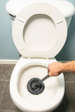 unclogging clogged toilet with plunger 