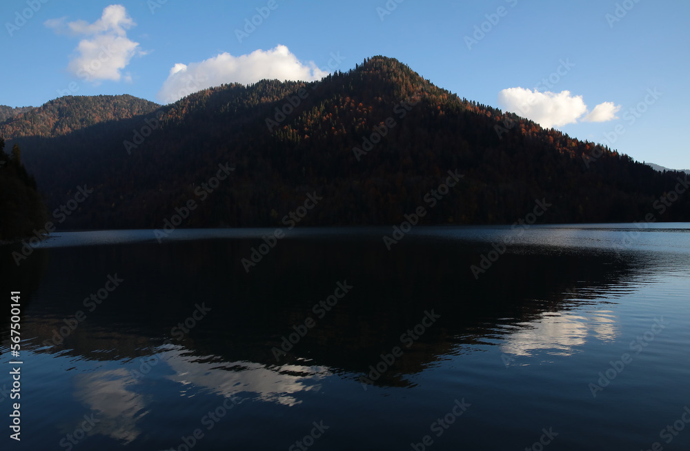 A lake in the mountains with a mirror image of the silhouette of a high hill on the water surface